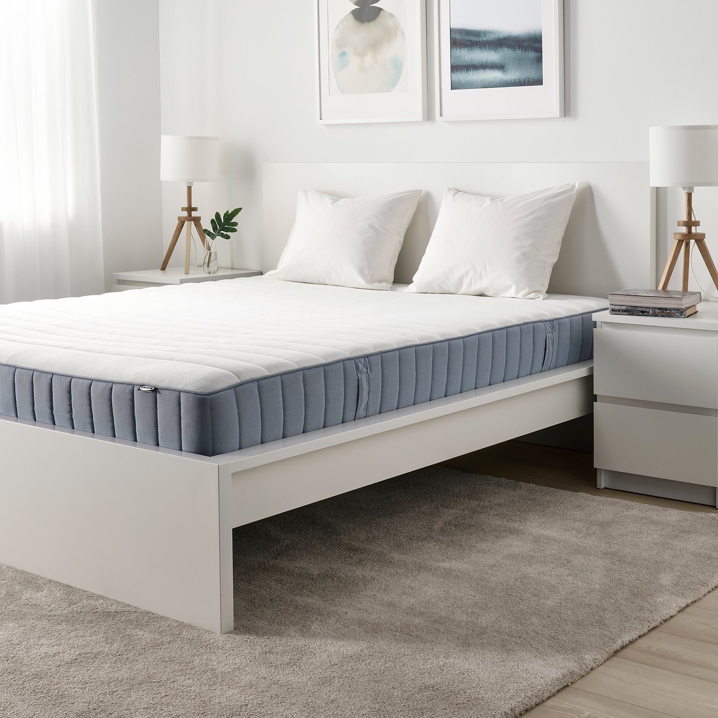 Modern bedroom with white VALEVÅG bed, pills, nightstands, and grey rug. Art on wall.