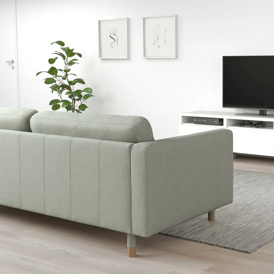 Grey-green LANDSKRONA sofa, large cushions, wooden legs. With white tv stand, plant, wall art. Sofa looks large.
