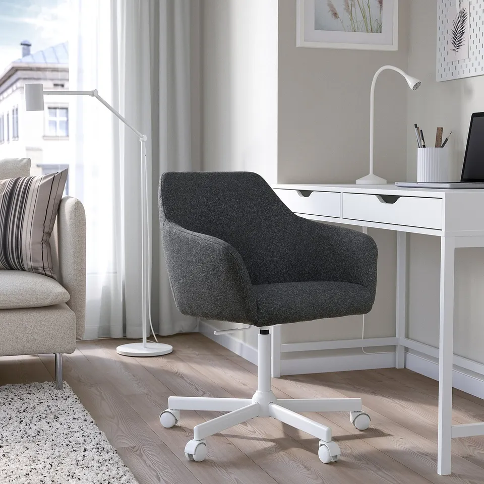 Modern home office setup with TOSSBERG grey chair, white desk, and lamp. Cosy and stylish.