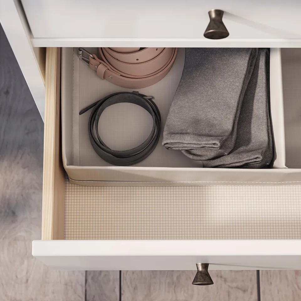 Open drawer with organised belts and folded grey clothes.
