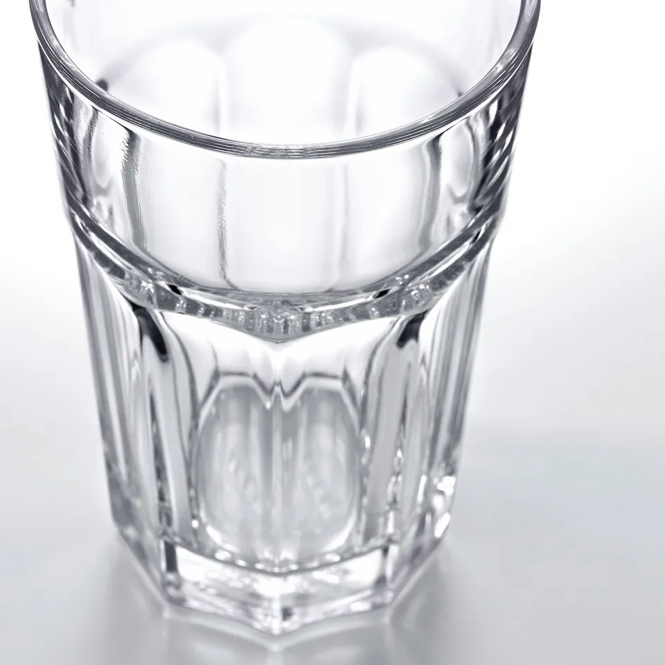 Clear glass tumbler with ridged sides and thick bottom, well-crafted, shown against white background.
