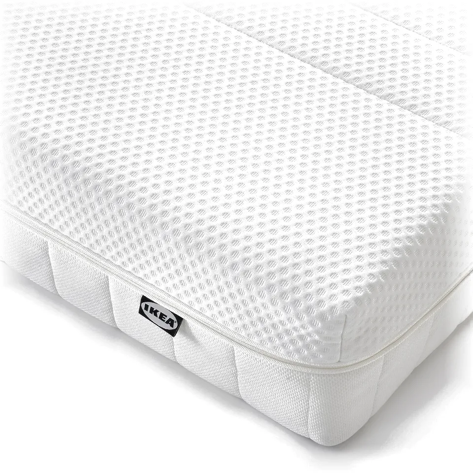 Crisp white foam mattress, neat and well-cushioned, with IKEA label, ensuring comfort and quality.