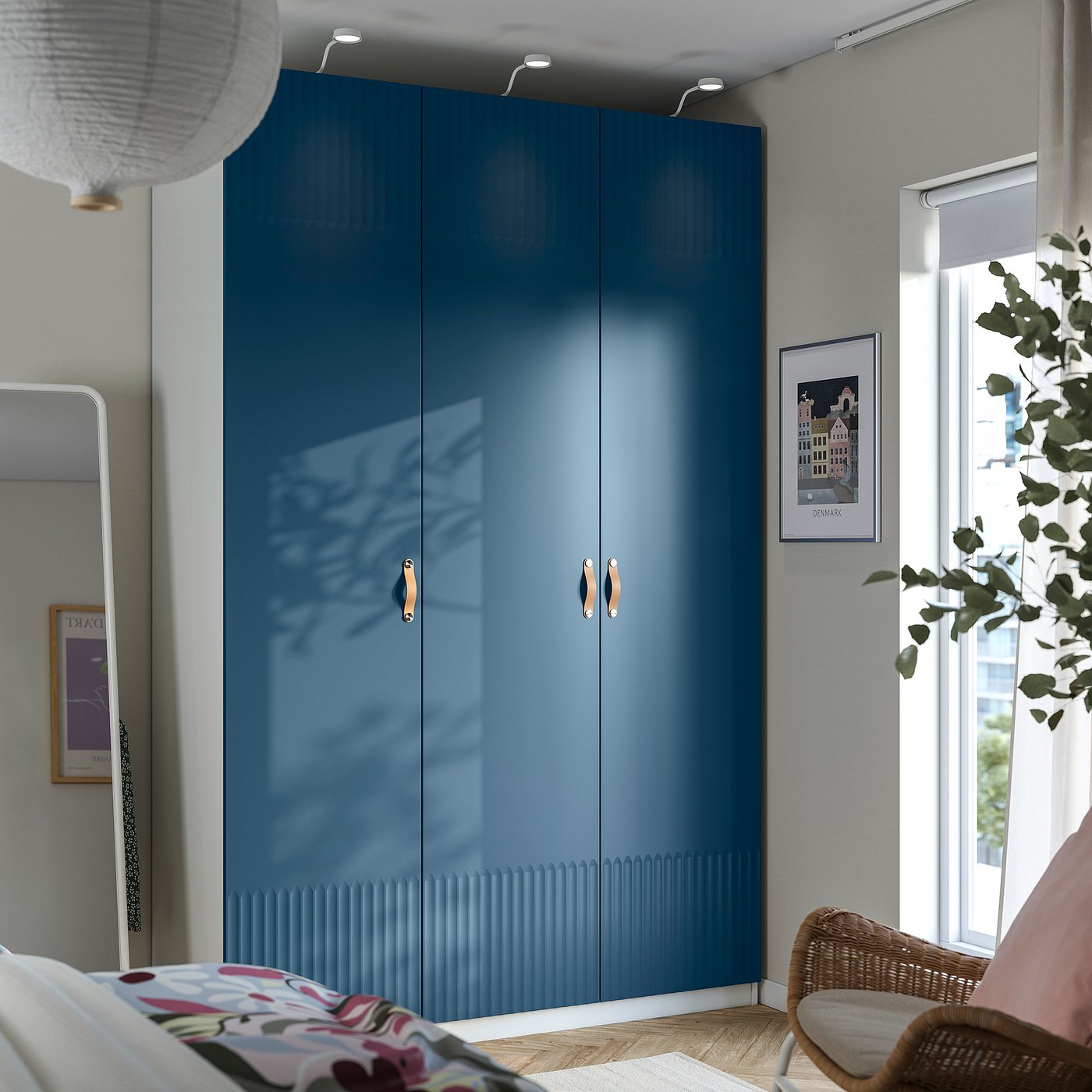 Modern bedroom with large blue PAX wardrobe, wicker chair, and floral pillow.