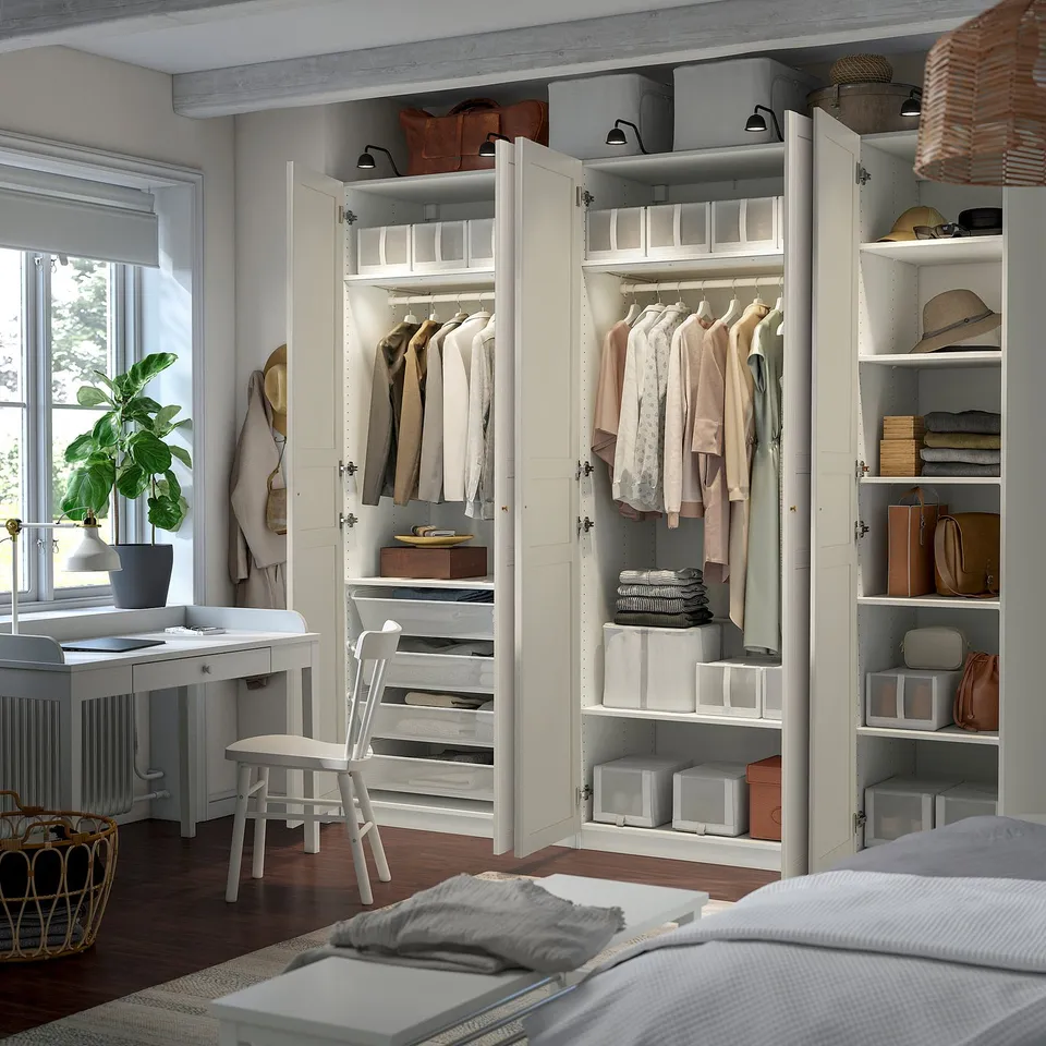 A well-organized bedroom with a PAX wardrobe, featuring shelves for folded clothes, hanging space, and integrated lighting.