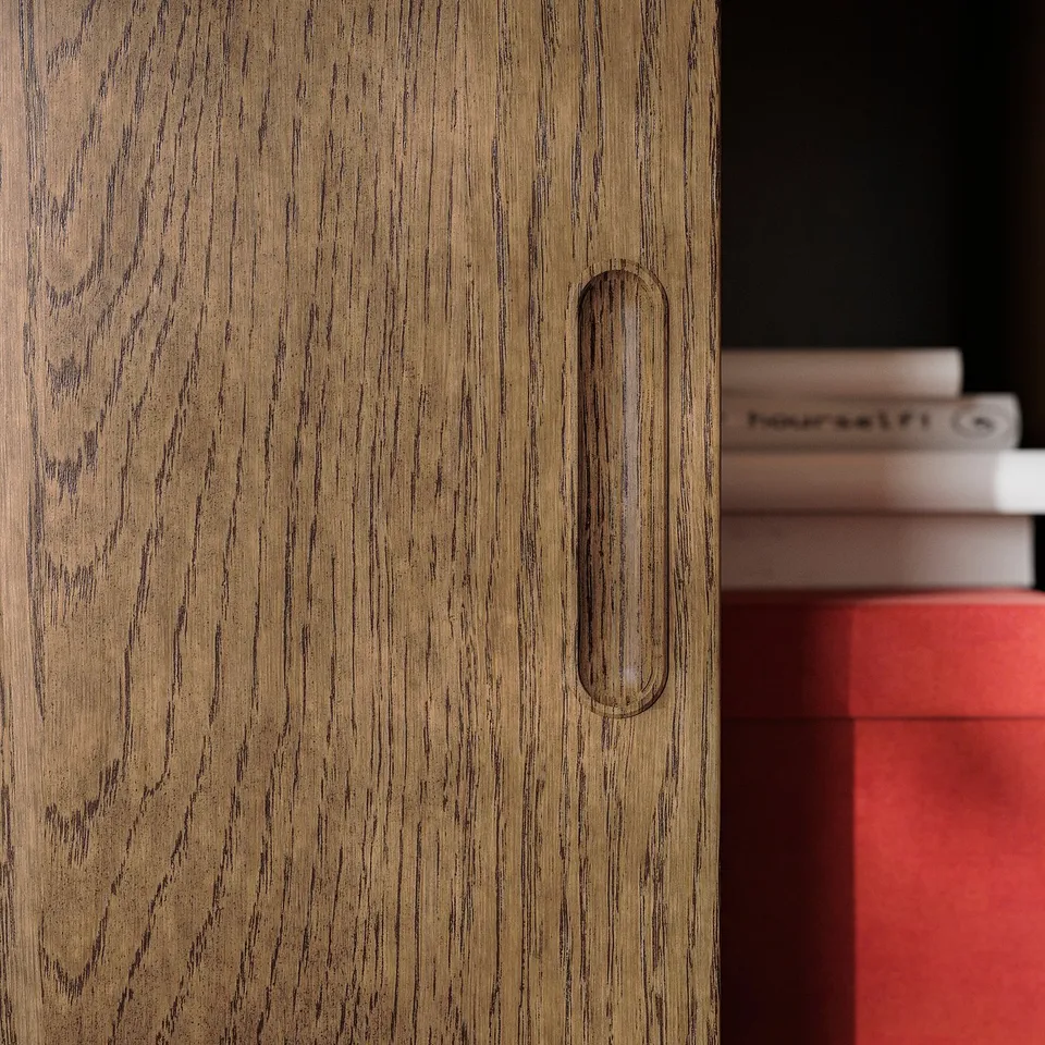 Wooden cabinet with smooth, integrated handle. Brushed veneer finish and sliding doors. Books visible on the right.