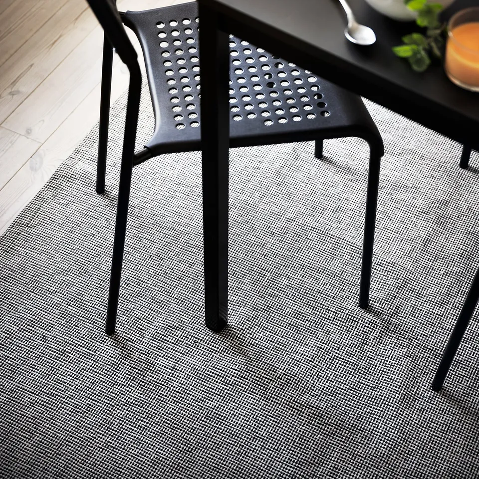 Black modern chairs on a grey textured rug.
