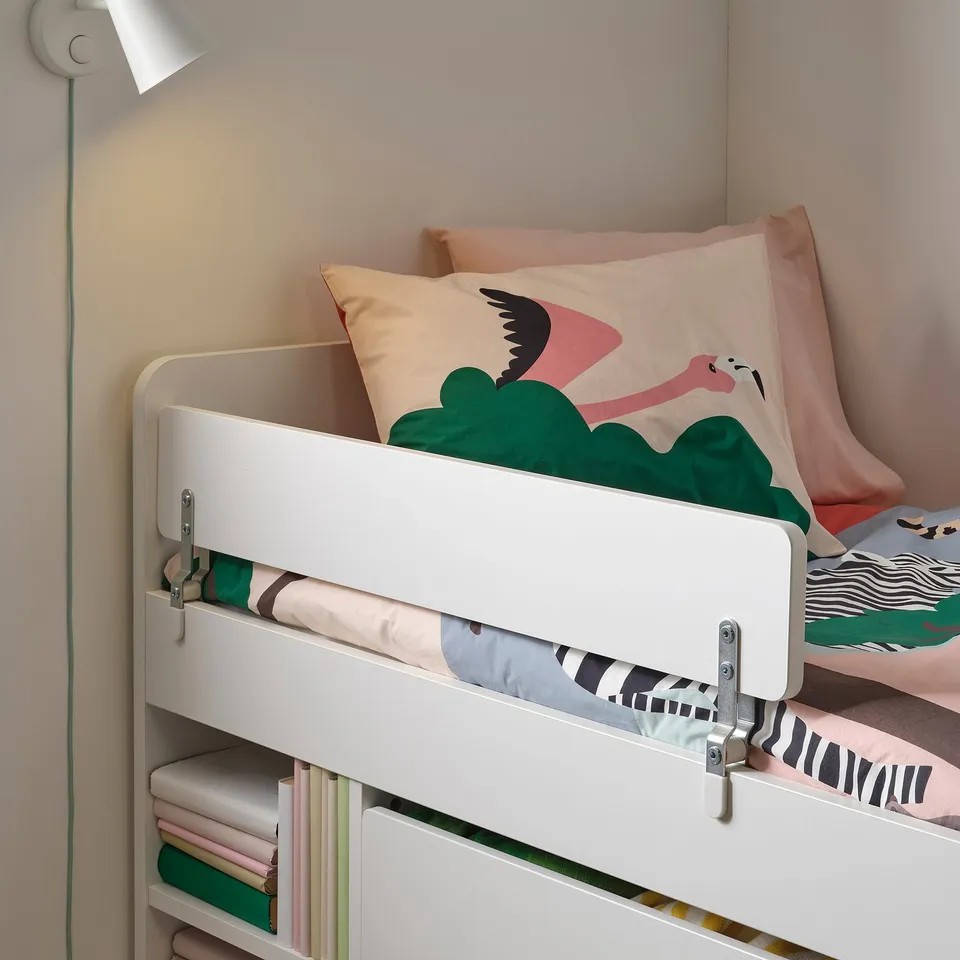 White kids bed with zebra bedding and flamingo pillow, guardrail, wall lamp