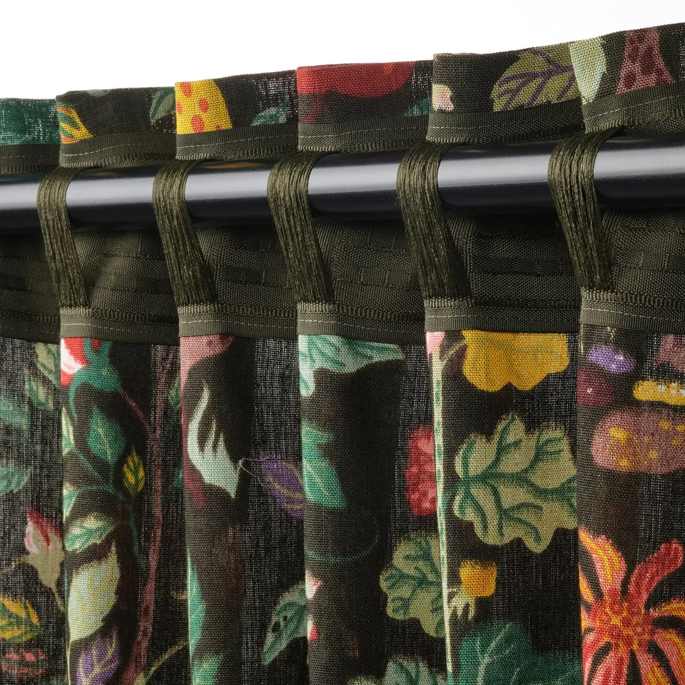 Close-up of VILDPERSILJA curtains with pleated tape and looped hooks, floral pattern on black-green base.