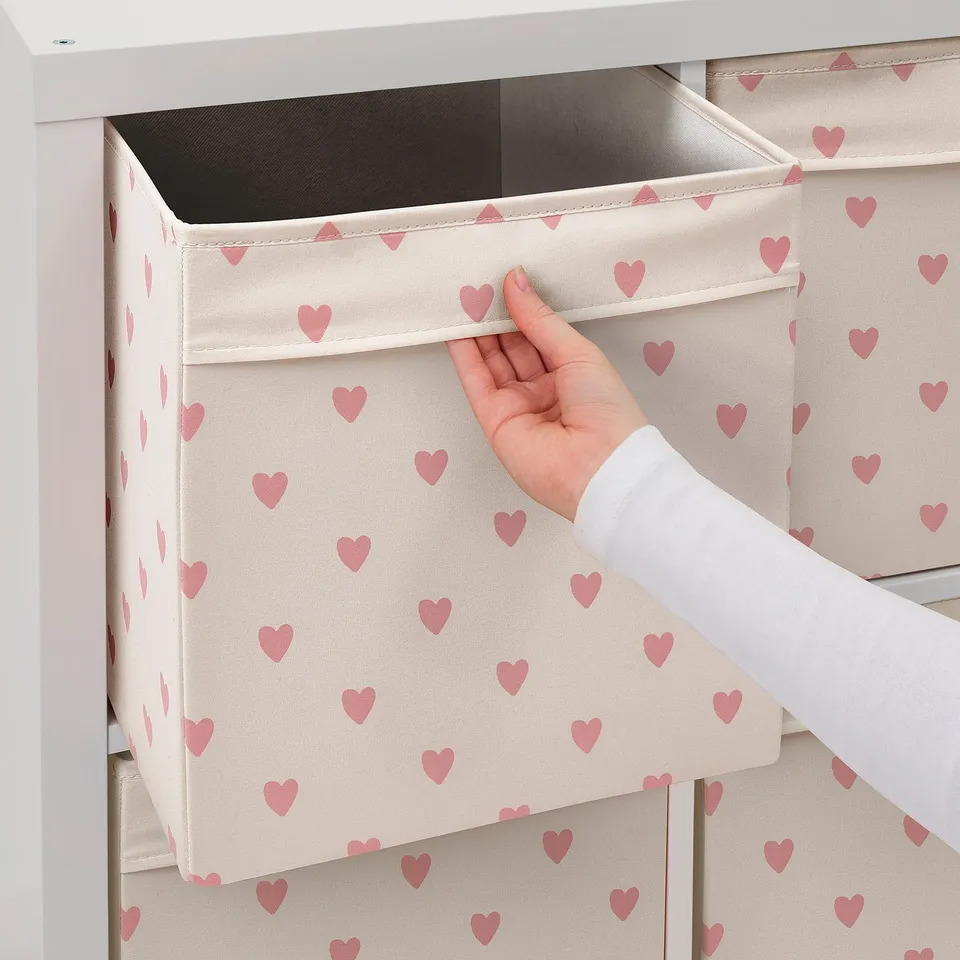 Hand pulling out fabric heart-patterned storage box from shelf.