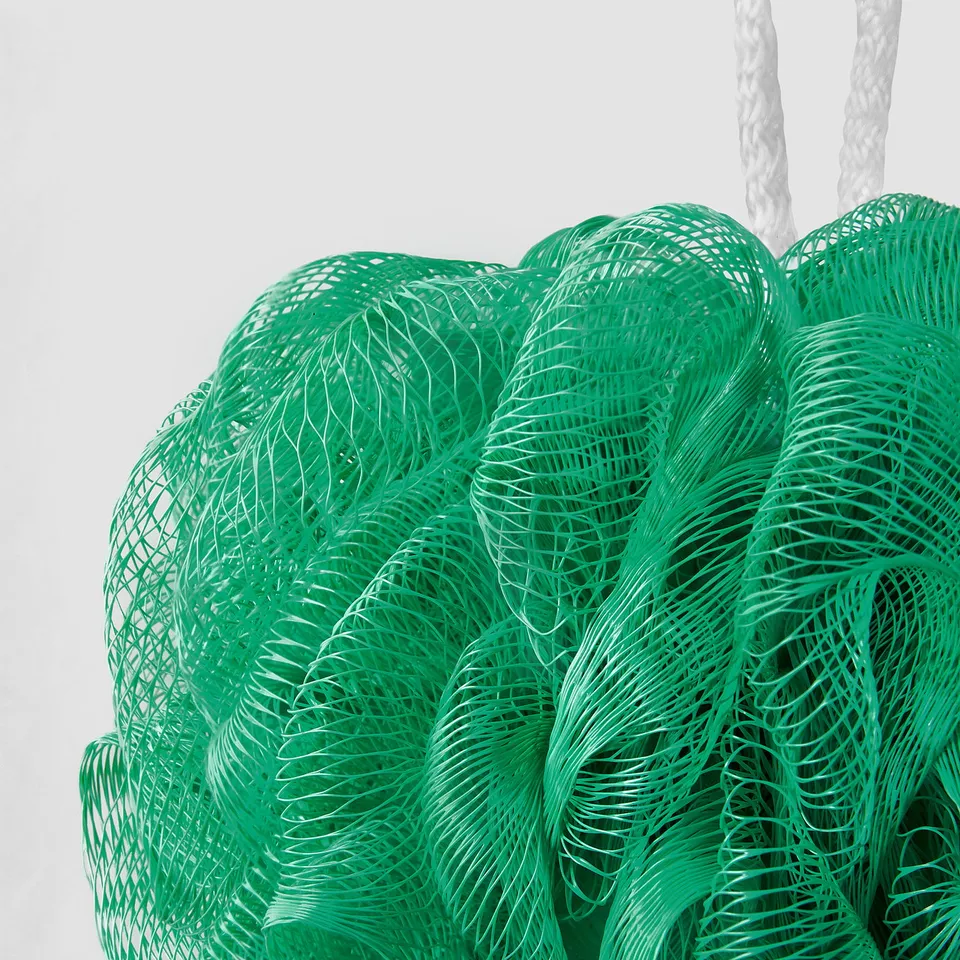 Three green mesh body puffs hanging, vibrant, fresh, ready for use.