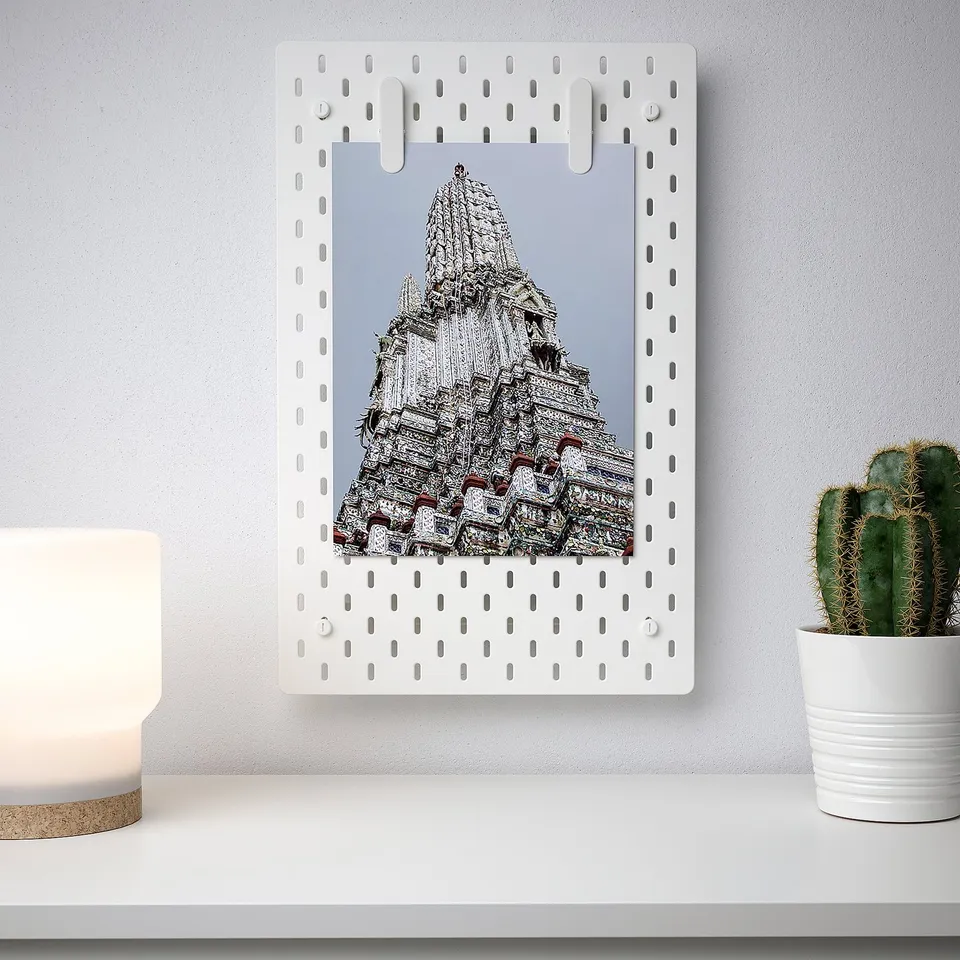 White pegboard SKÅDIS displaying photo, lit lamp, cactus.