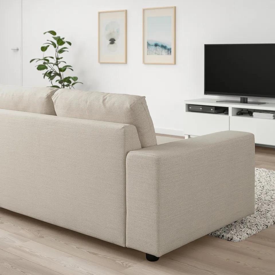 Modern beige VIMLE sofa in minimalist living room, beside large tv, with potted plant.