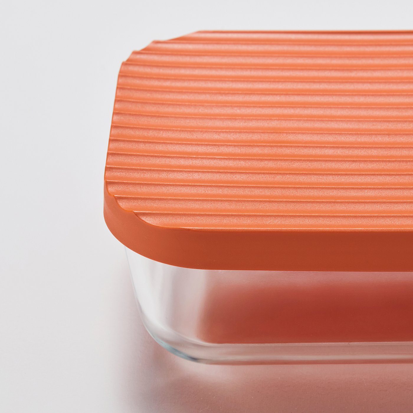 Close-up of a clear glass container with an orange lid, showing its smooth texture and secure fit, highlighting its durable and valuable quality.