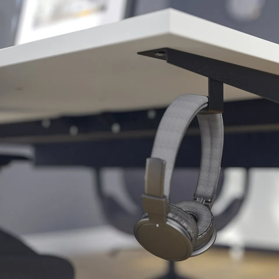 Headphones hang neatly on MITTZON desk hook, keeping workspace tidy.
