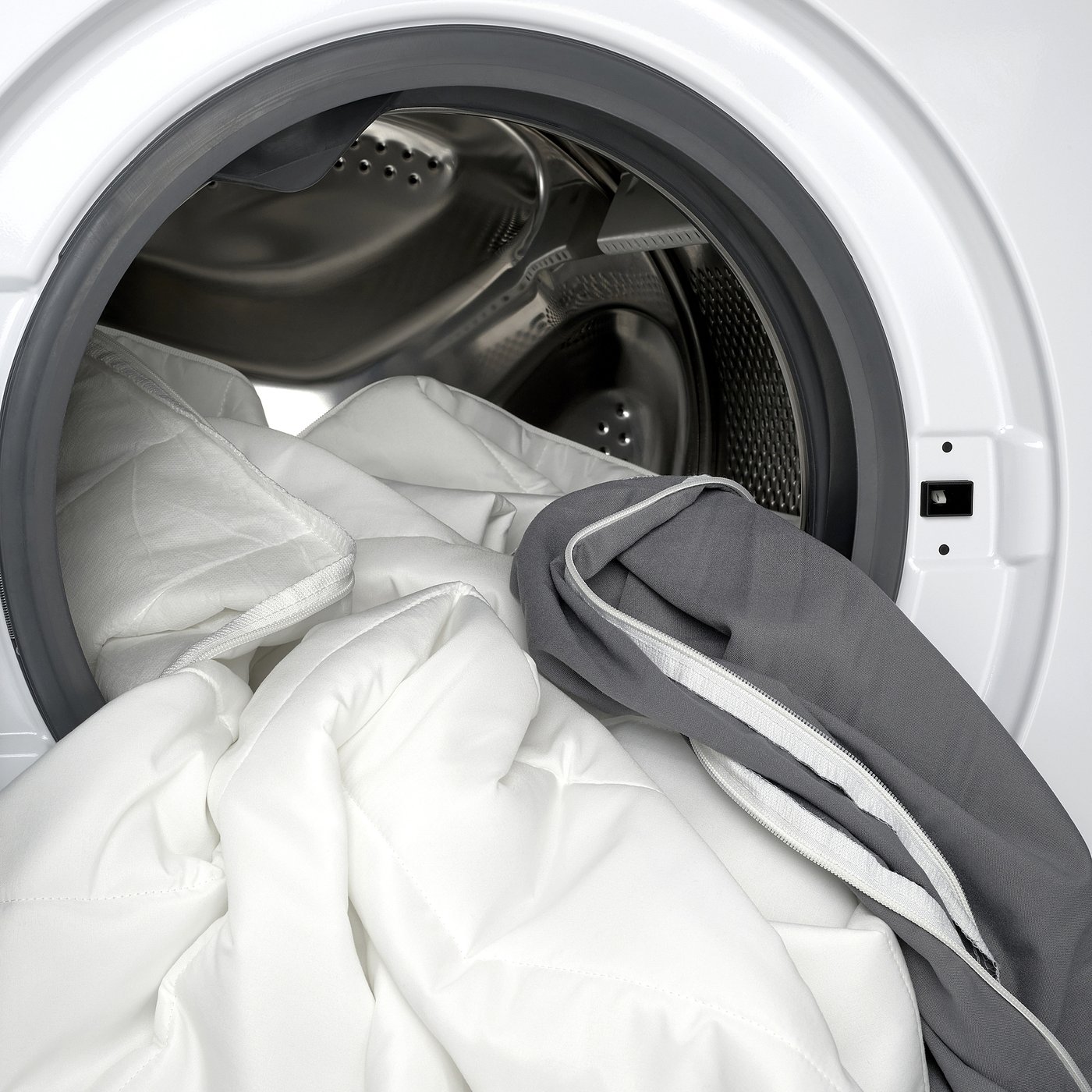 Washing machine with quilted pad and grey blanket.