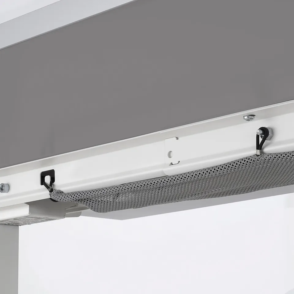 Close-up of robust, white, metal desk support with perforated cable management tray.