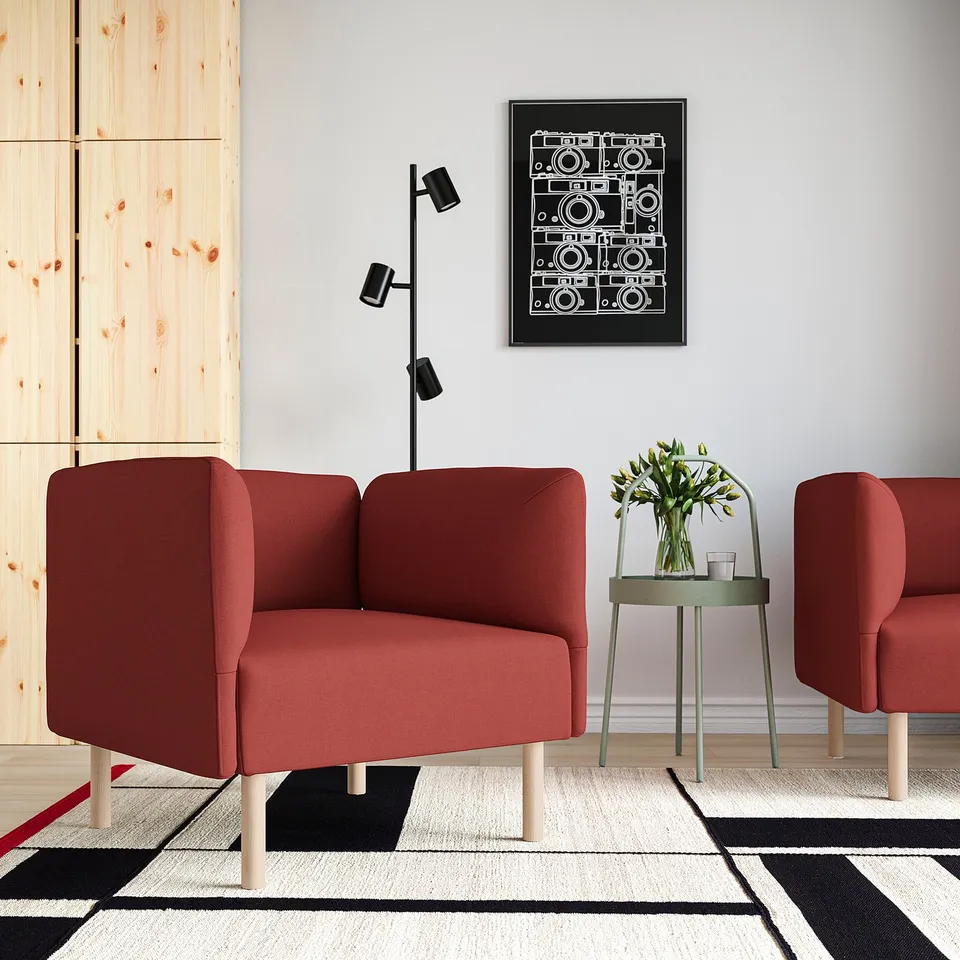 Red armchairs on rug, green side table with flowers, black poster, wall lamp, minimalist room with wooden partition.