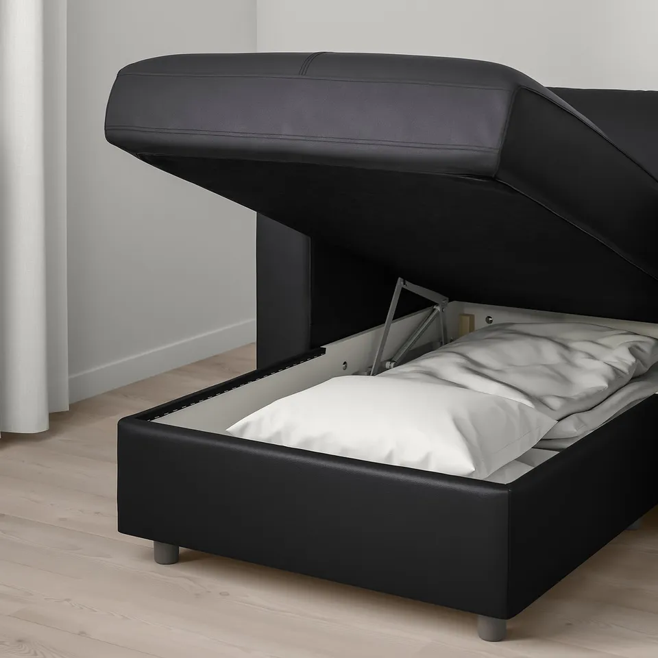 Black leather bed with storage lifting mechanism. White pillows indicate open storage space.