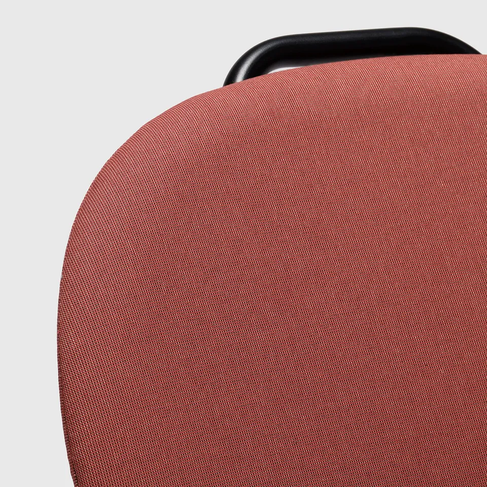 Red upholstered office chair back, sturdy, comfortable with black top handle.