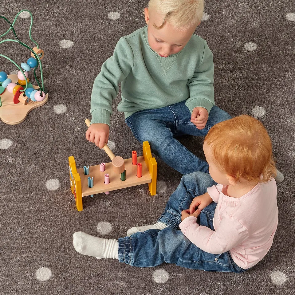 Children playing with hammer block on carpet.