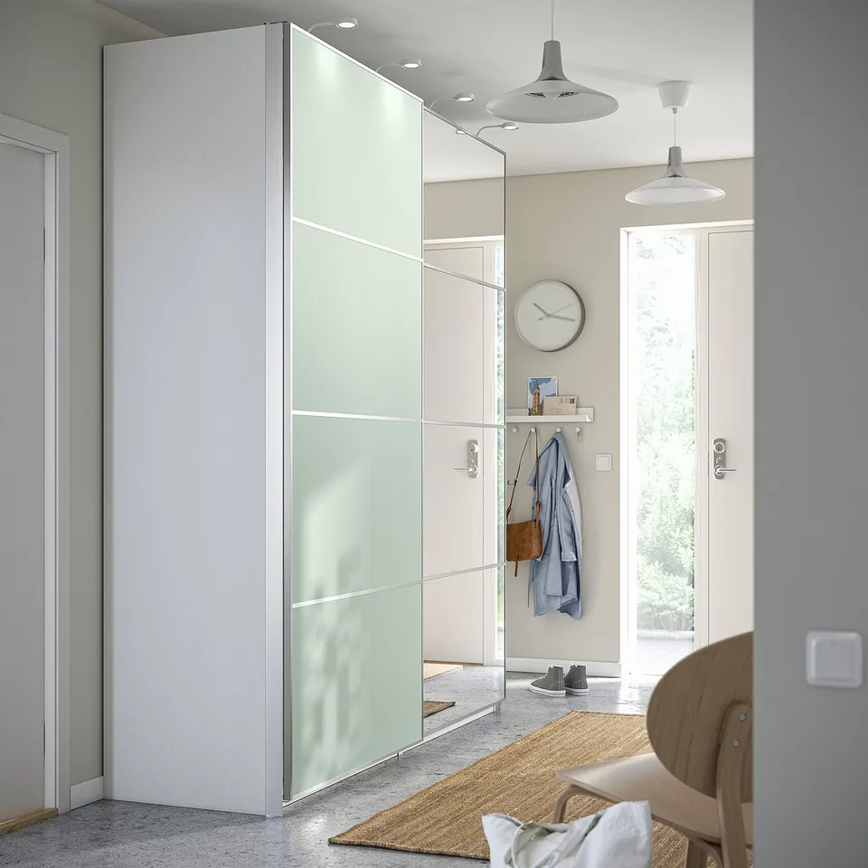 Modern entryway with PAX wardrobe, clock, chair, and coat hooks. Door opens to garden.