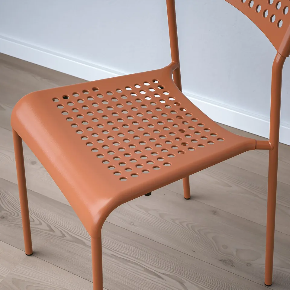 Bright orange plastic chair with a perforated seat and back for breathability. Stackable design, suitable for modern indoor spaces.