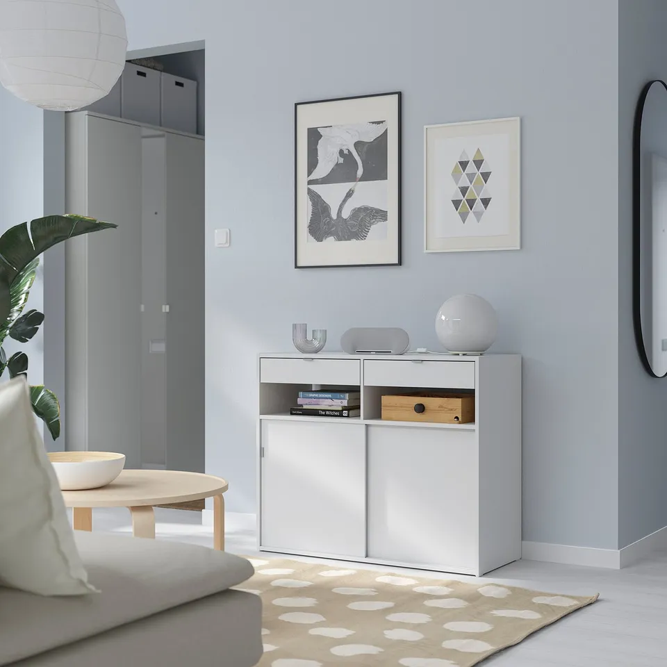 Modern minimalist living room with white SPIKSMED sideboard, versatile storage, grey wall, art, mirror, and sofa.