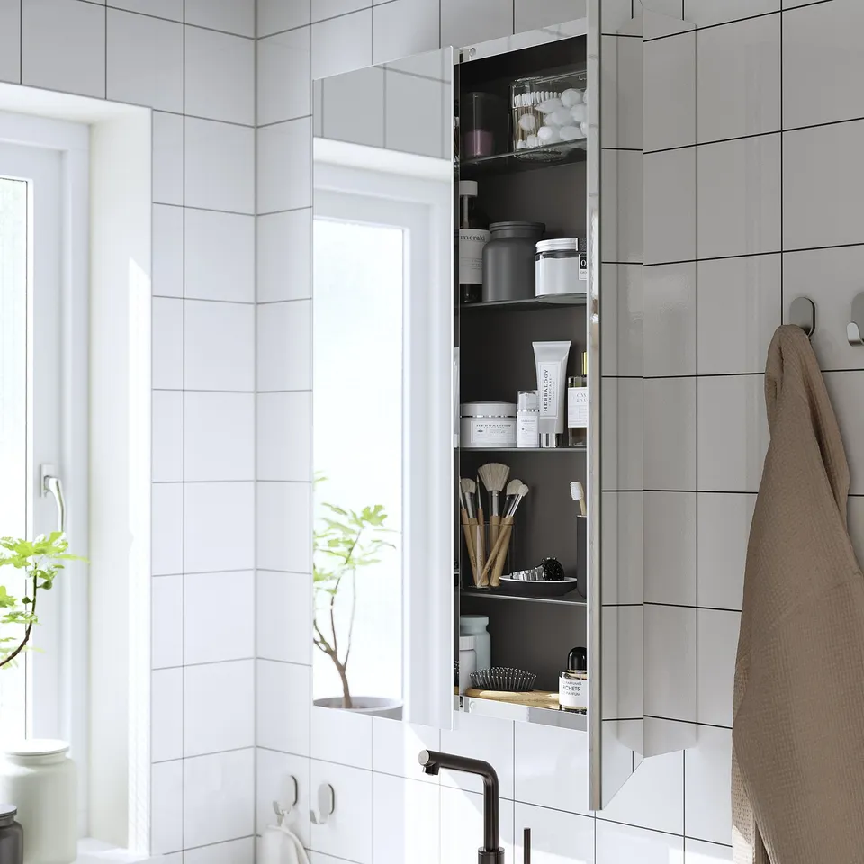 Mirrored cabinet for toiletries, sleek design, reflects light.