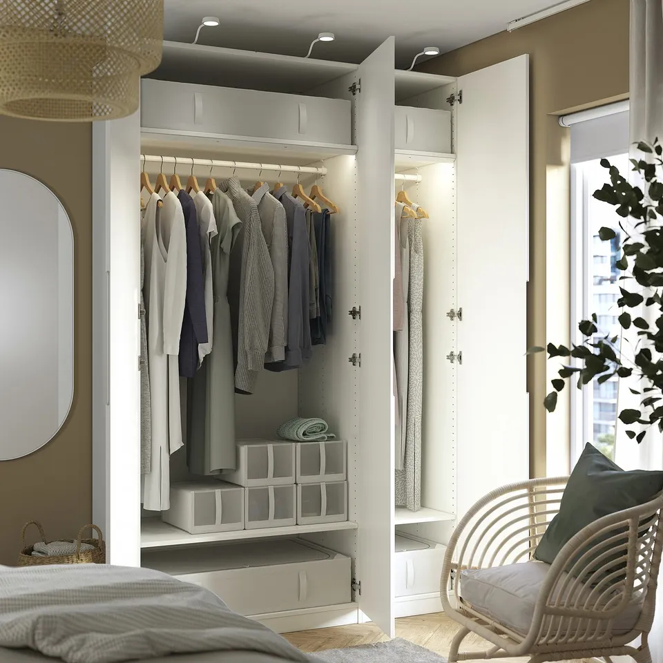 Open wardrobe with clothes, shelves, and storage boxes. Integrated lighting, adjustable feet, and soft-closing hinges visible.