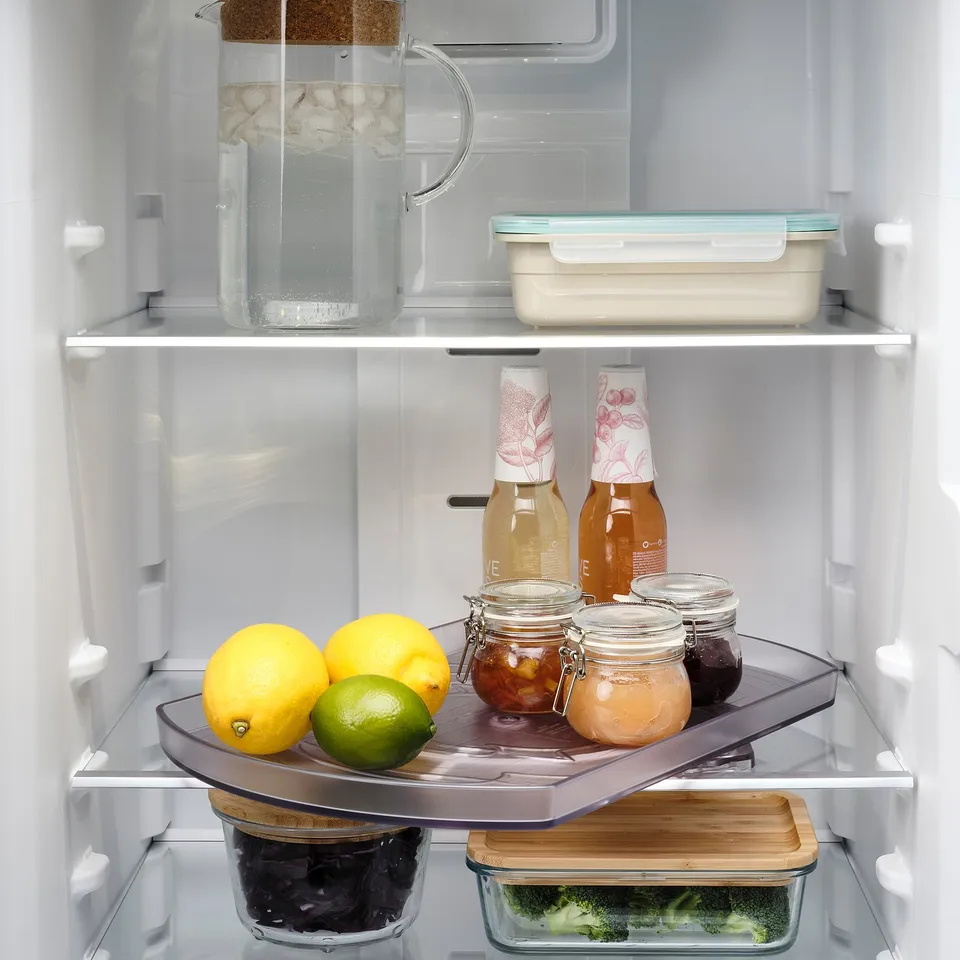 Fridge turntable with lemons, limes, jars, and containers. Keeps contents visible and accessible.