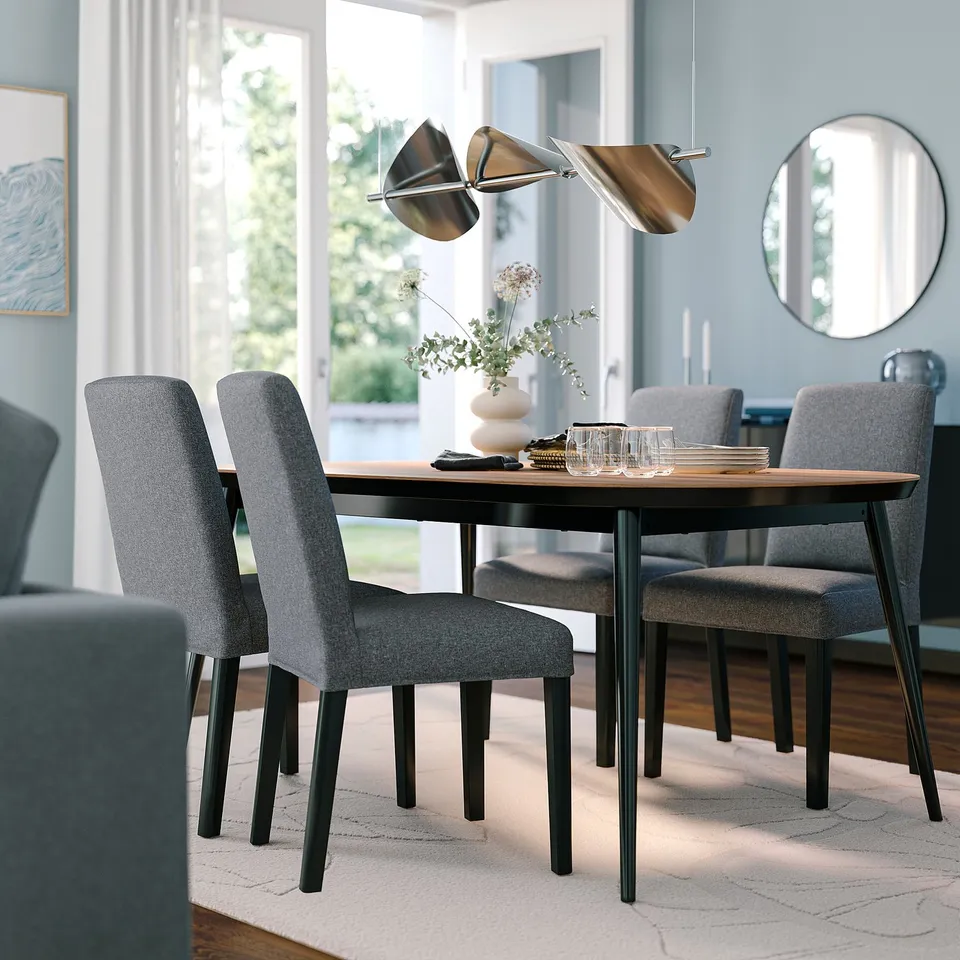 Modern dining set: TJÄRKIL. Round table with dark base, sleek grey chairs. Sophisticated lighting, roomy, clean lines.