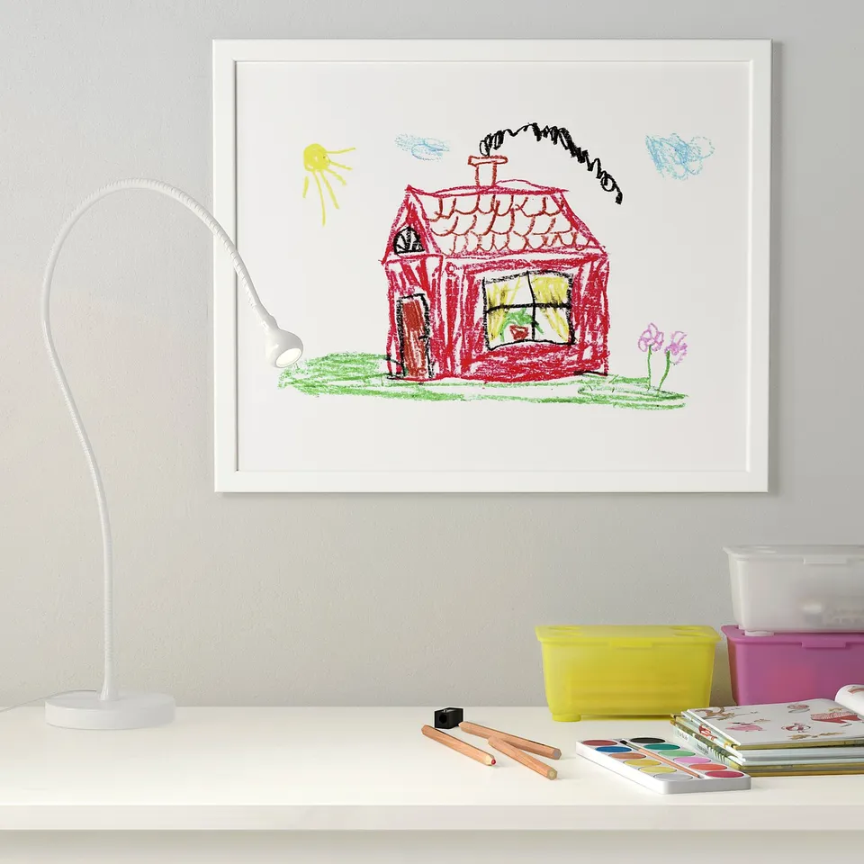 Framed childs drawing with lamp and art supplies.