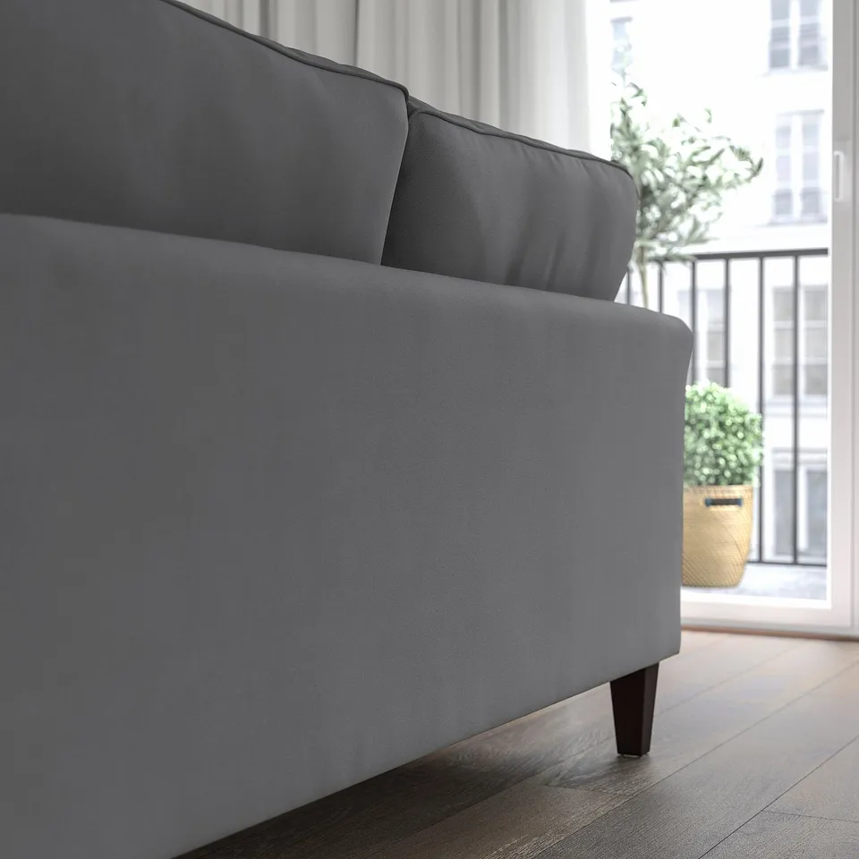 Grey EKHOLMA sofa near window with plant. Upright seating, soft cushions, removable cover.