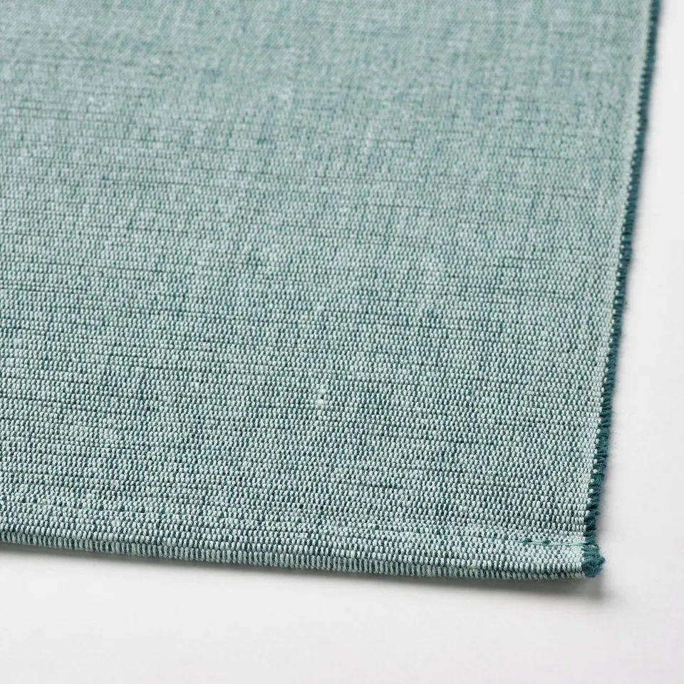 Light teal woven place mat, texture visible, edge stitched detail.