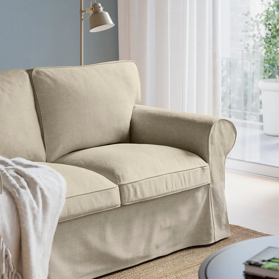 A cosy beige EKTORP armchair with plush cushions, set near a window offering a comfortable spot to relax.