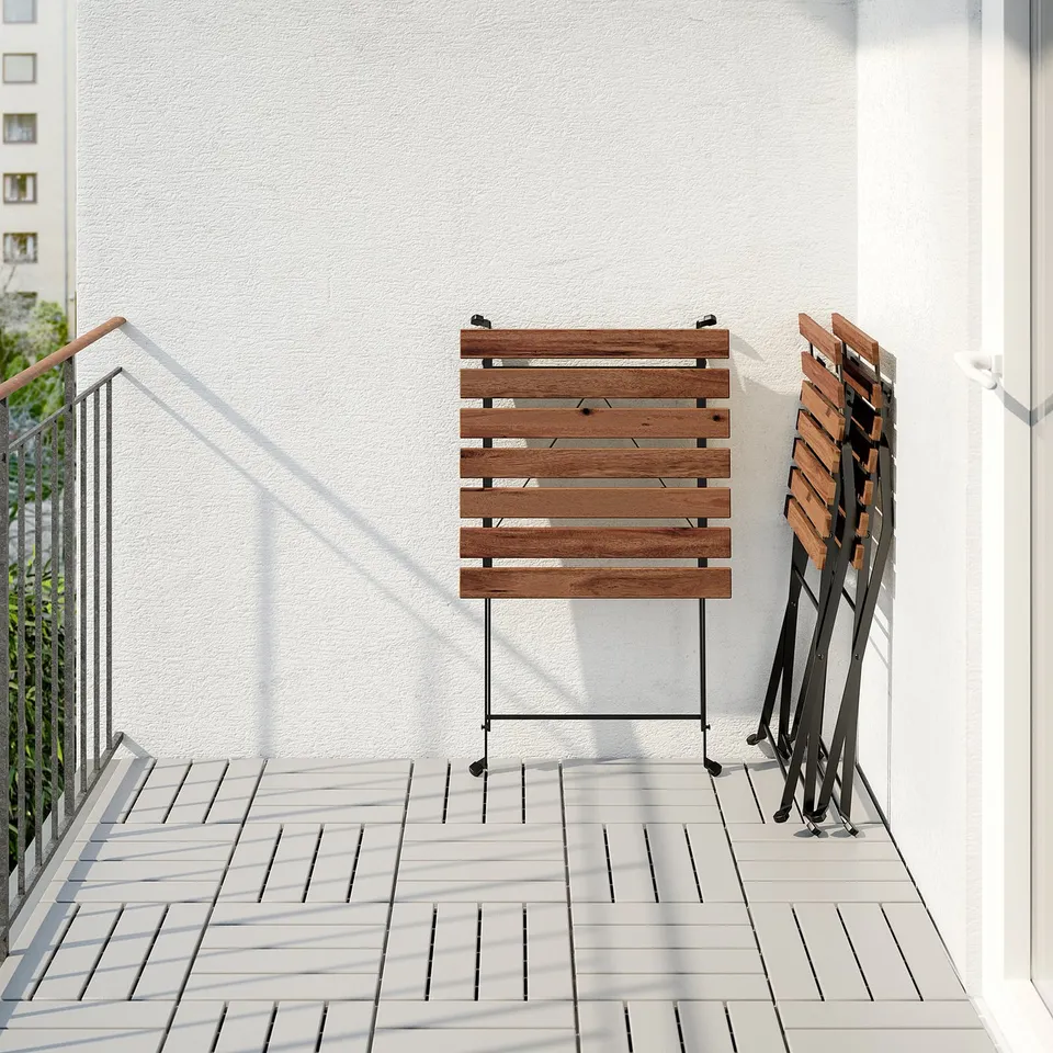 Wooden TÄRNÖ table and chairs folded, stored on balcony.