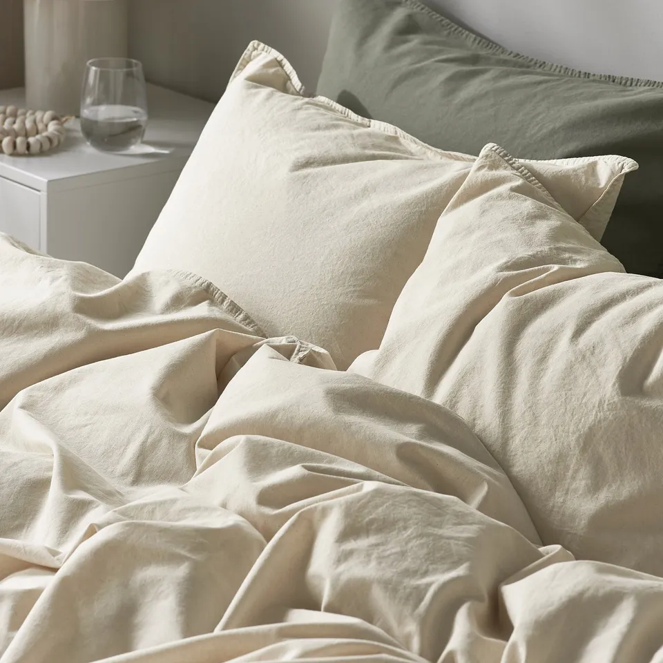 Crisp, cream-colored bedding with ruffled edges, showing soft, inviting texture.
