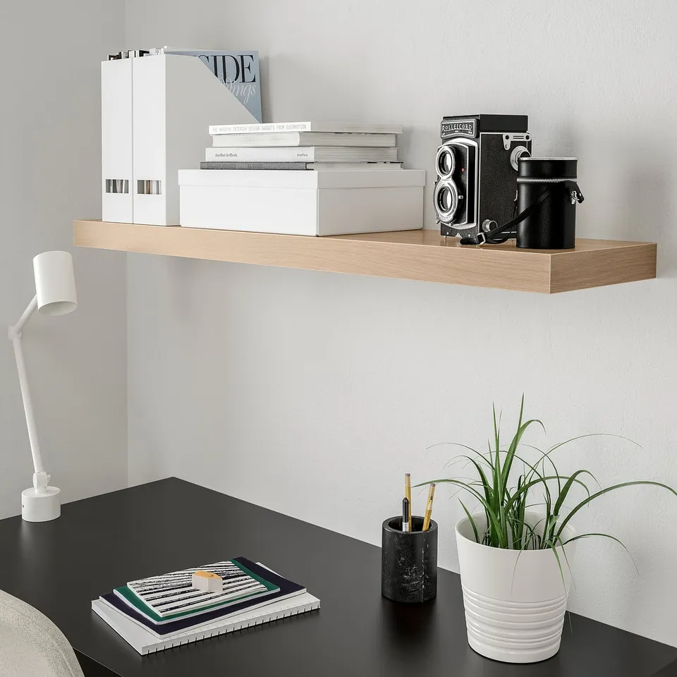 Minimalist desk with LACK shelf, books, camera, lamp, plant.
