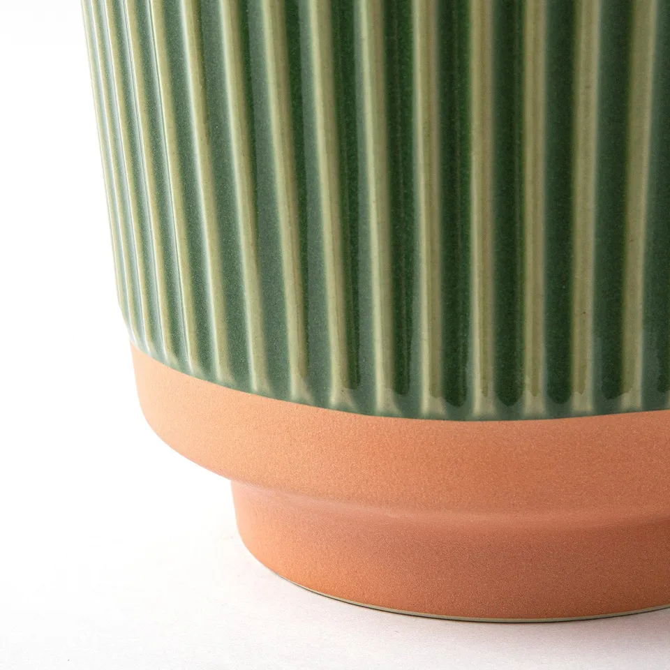 Green vase with vertical ridges on terracotta base