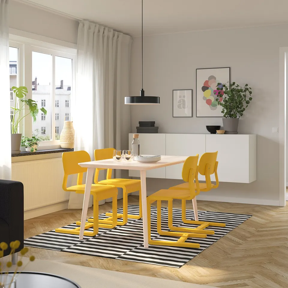 Modern dining setup with LISABO table and yellow chairs, natural wood and veneer finish, stripy rug, hanging lamp, and artistic wall decor.