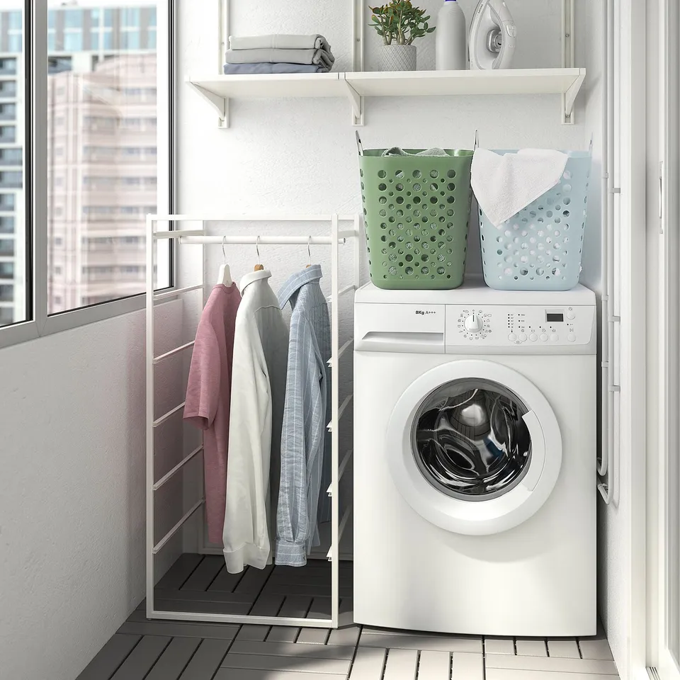 Laundry area with washing machine, drying rack, and color-coded baskets.