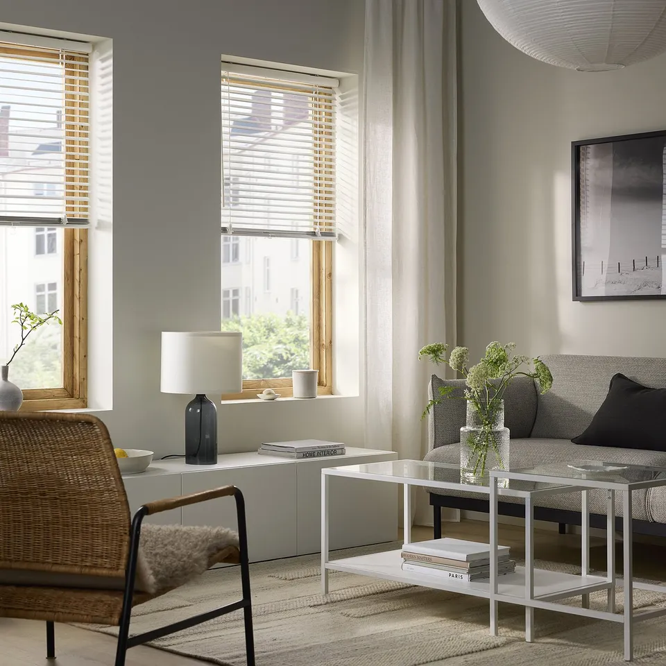 Modern living room with large VECKLARFLY blinds, grey sofa, coffee table, and white lamp; sleek and minimalistic design.