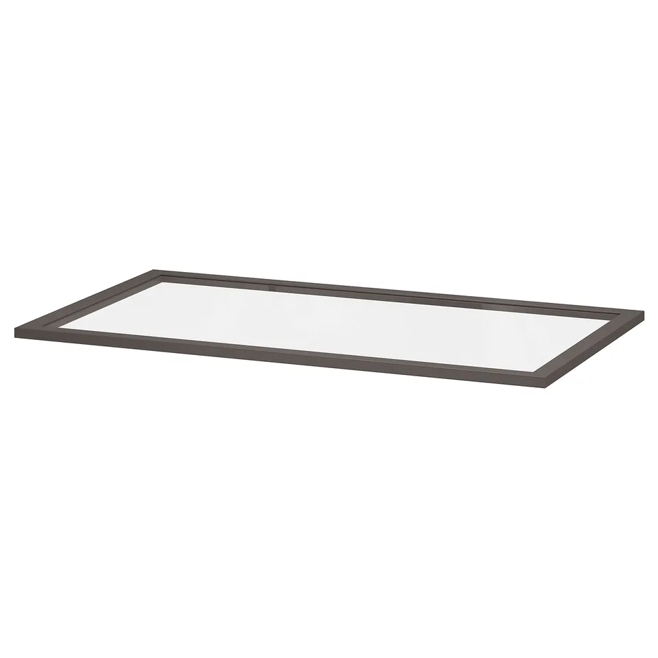 A clear glass shelf, framed with dark grey fiberboard, ideal for organising and displaying items neatly.