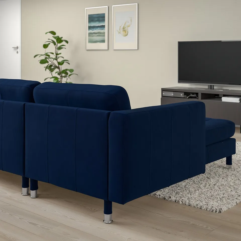Modern living room with navy sofa, chaise, grey rug, tv, and art.