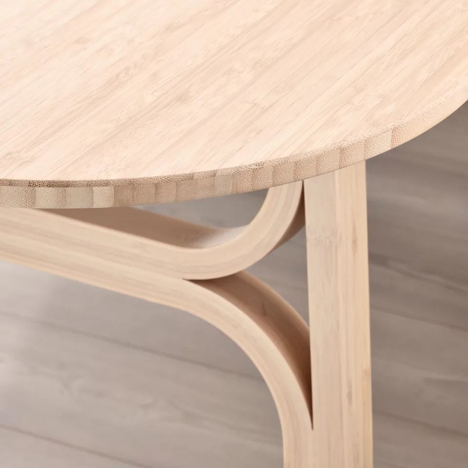 Sleek, modern table edge showcasing smooth, light bamboo finish. Curved underside supports visible.
