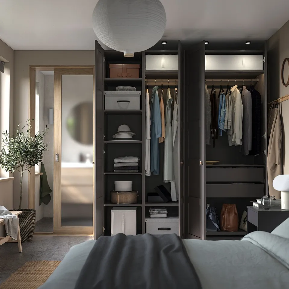Bedroom with open wardrobe, clothes, shelves. Grey bed, pendant light, natural light.