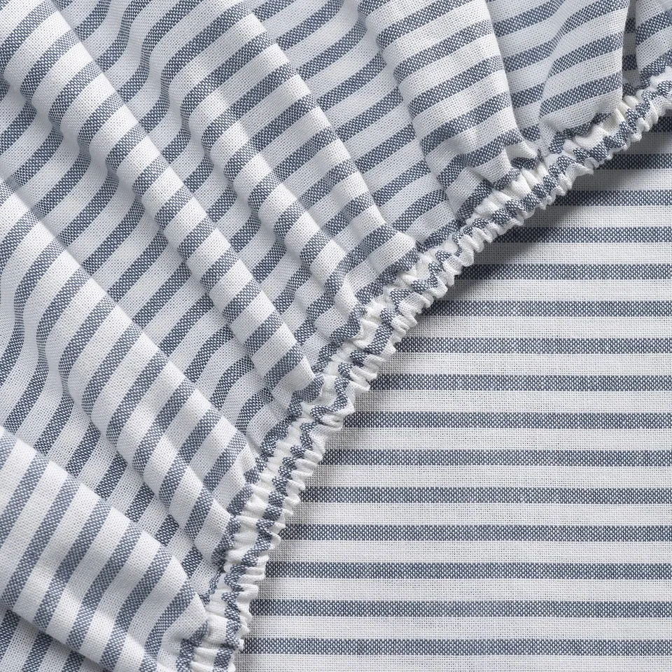Neatly made bed with striped blanket and ruffled edge.