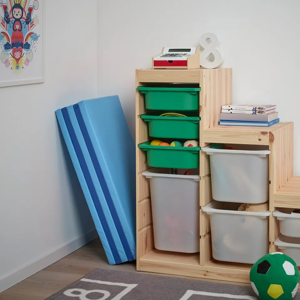 Wooden toy storage with colourful bins, holding books and toys. Blue padded mat leaned against wall, ideal for kids playroom.