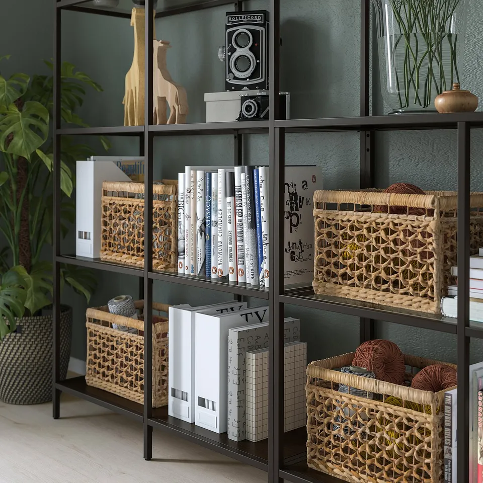 Black metal shelf with glass panels, holding books, baskets, decor, and a giraffe sculpture. Adjustable feet for stability.