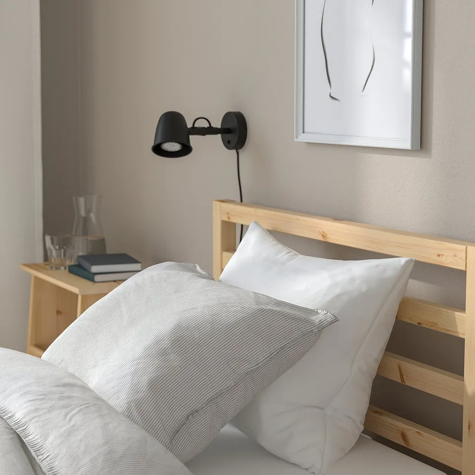 TARVA bed, white linens, black lamp, water carafe, books, abstract art, scandinavian calm.